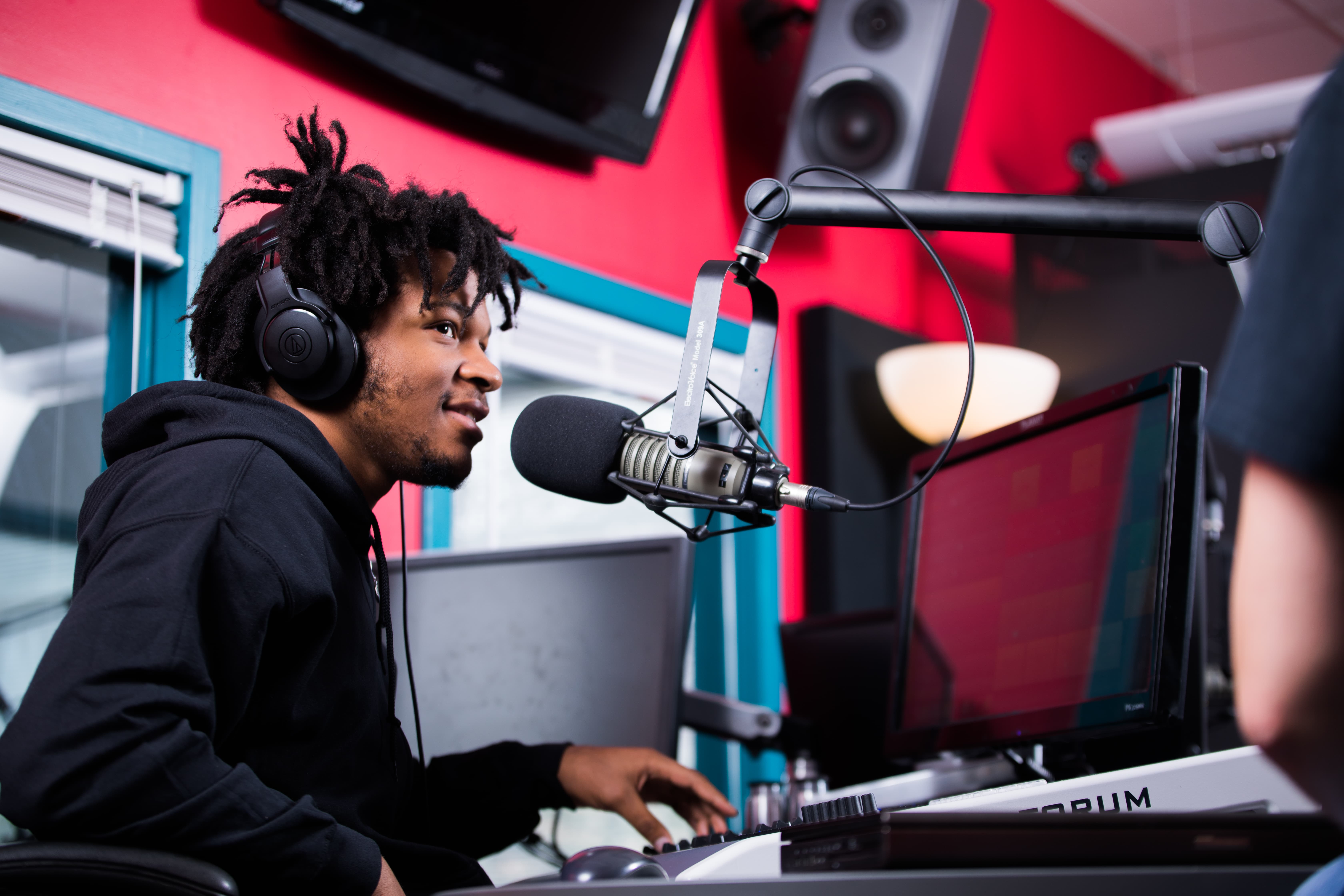 Communication student talking on the radio at a recording studio.