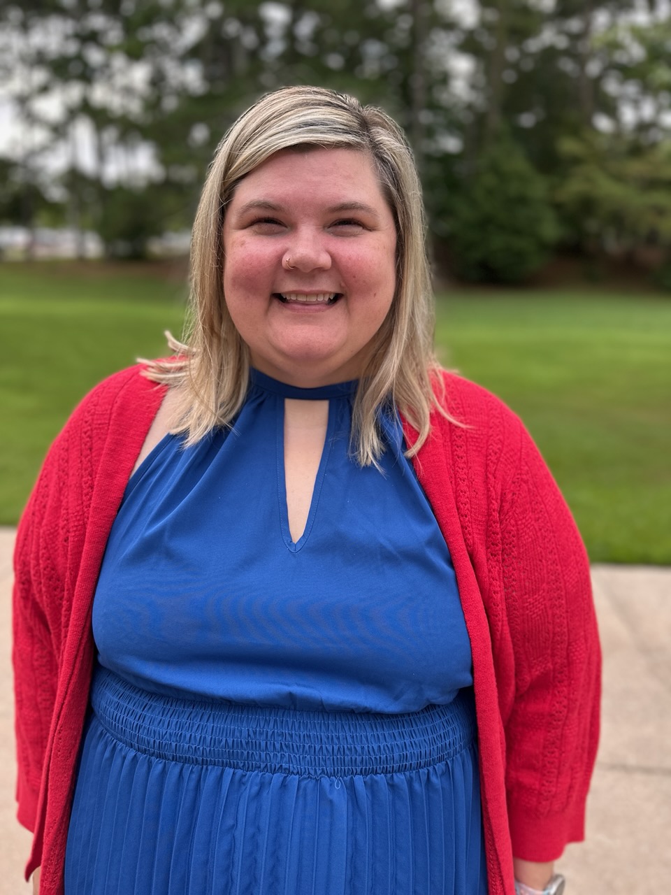 a profile picture of dr. brandy locchetta in a blue dress with a picture of a field in the back