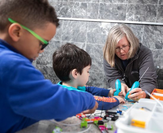 Teacher working with two children with electrical components