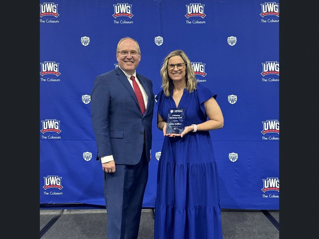Melissa Brillhart taking a picture with her award and the Provost