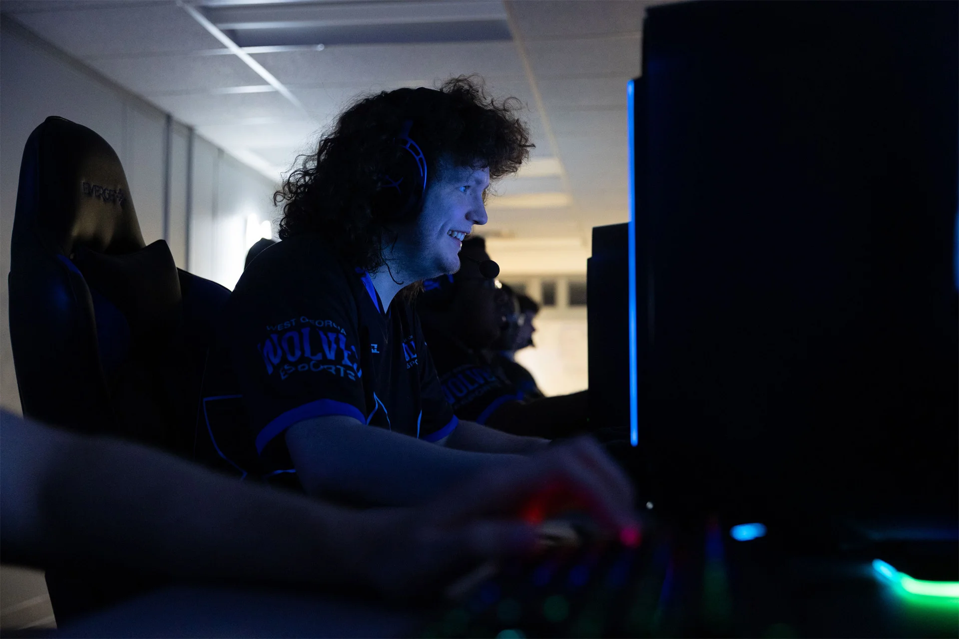 ESports team player sitting at computer smiling at the screen.