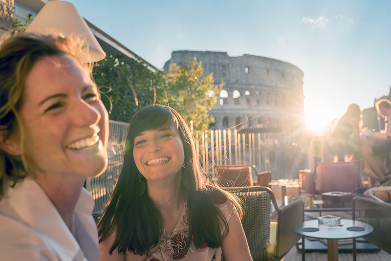 two females at a cafe in Rome with the Colisseum in the background
