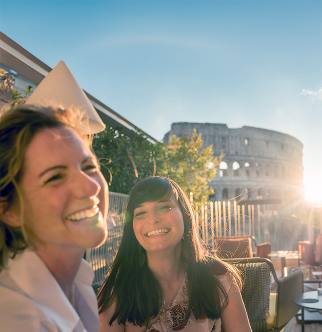 female student at a cafe in Rome with the Colisseum in the background