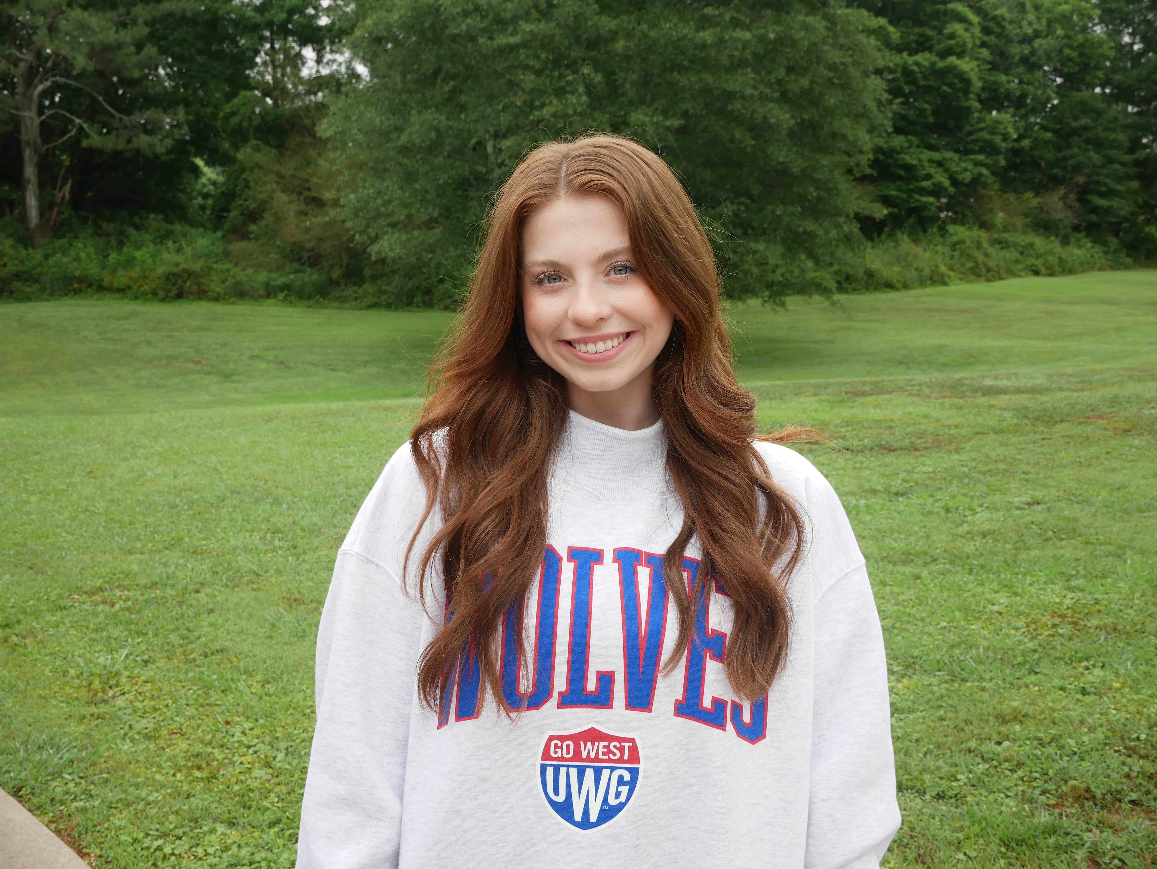 Kensley H. standing in a UWG sweatshirt in front of a grassy field