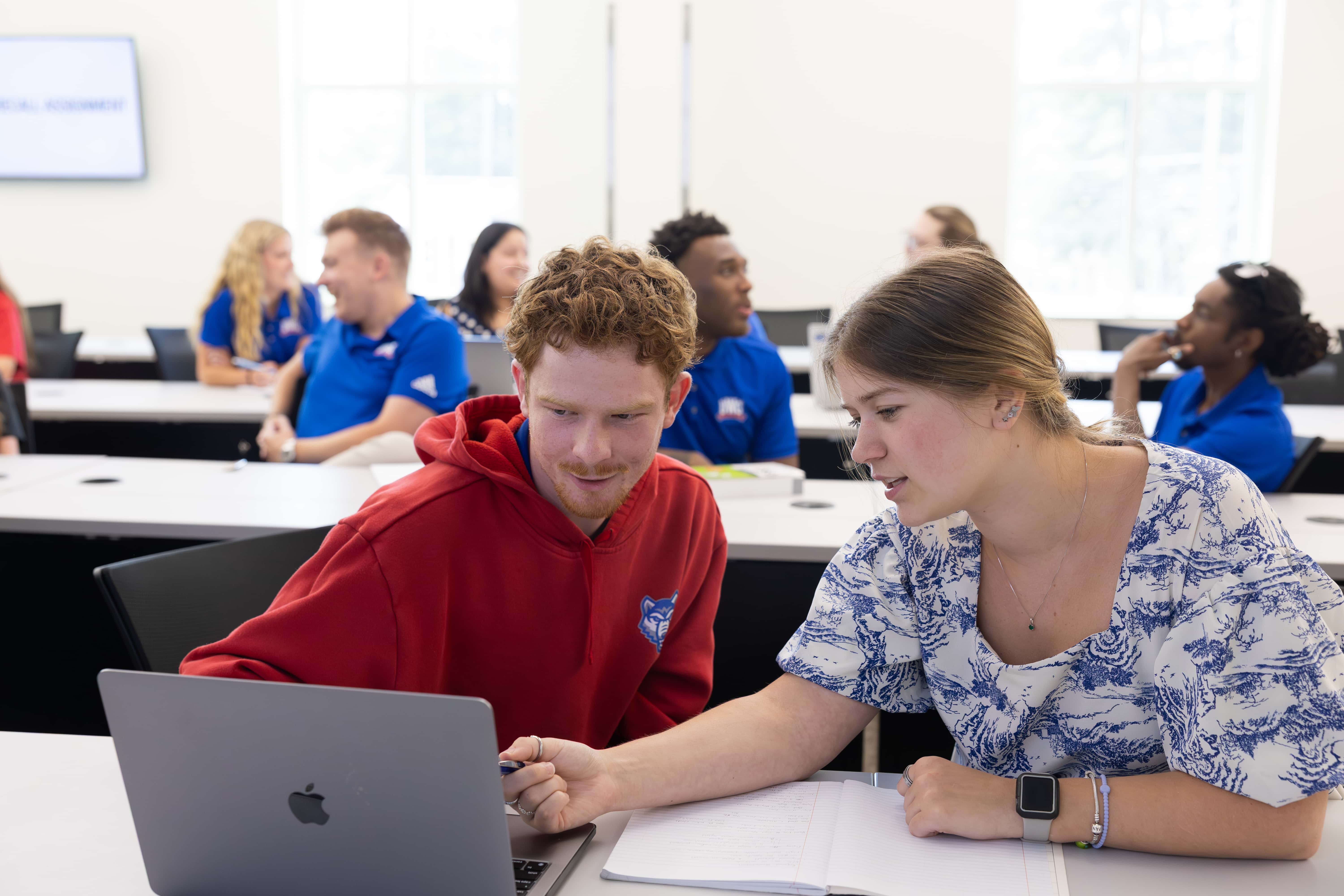 Two students looking at a computer screen in a classroom