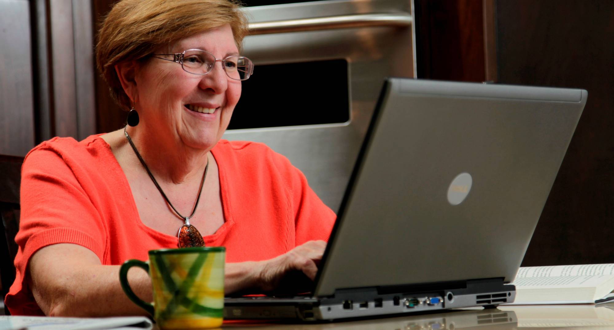 Lady looking at her computer in her kitchen.