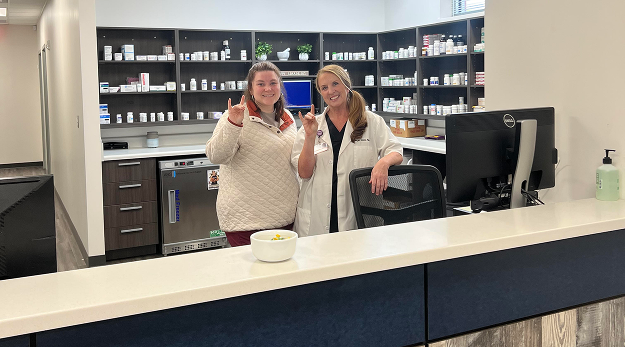 Pharmacy team behind Pharmacy counter holding up the wolf hand sign