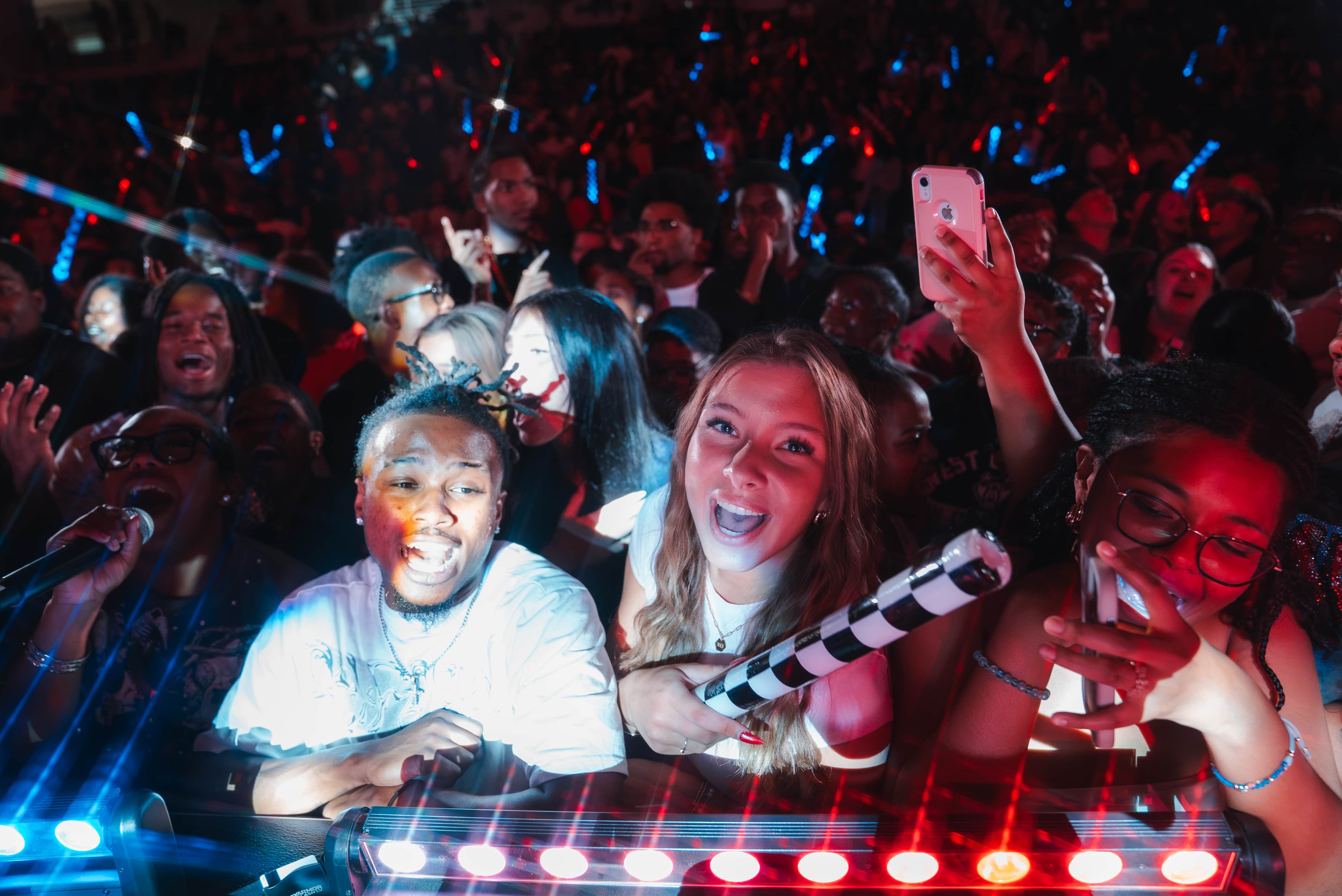 Students gathered in the coliseum for a concert during homecoming with red and blue lights across the crowd.