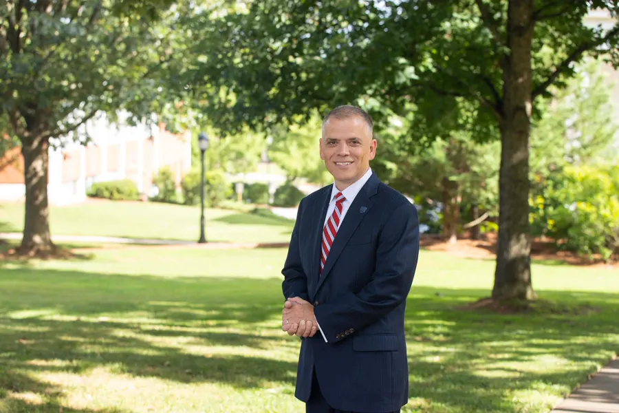 President Johnson standing outside for a professional photo, wearing a suit with a red and white striped tie.