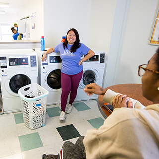 Two students talking and doing their laundry.