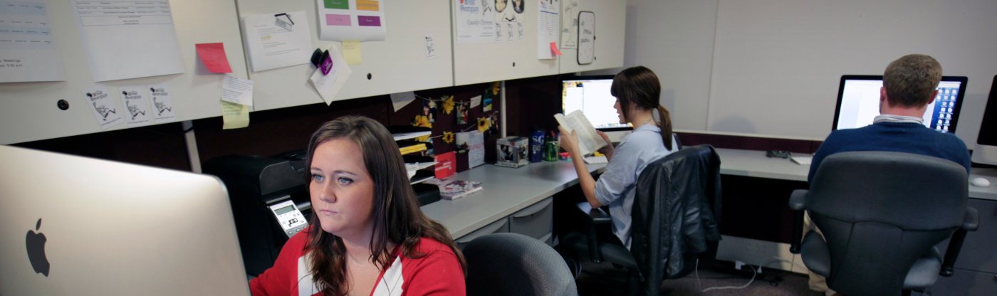 People sitting at countertop desks working on computers.