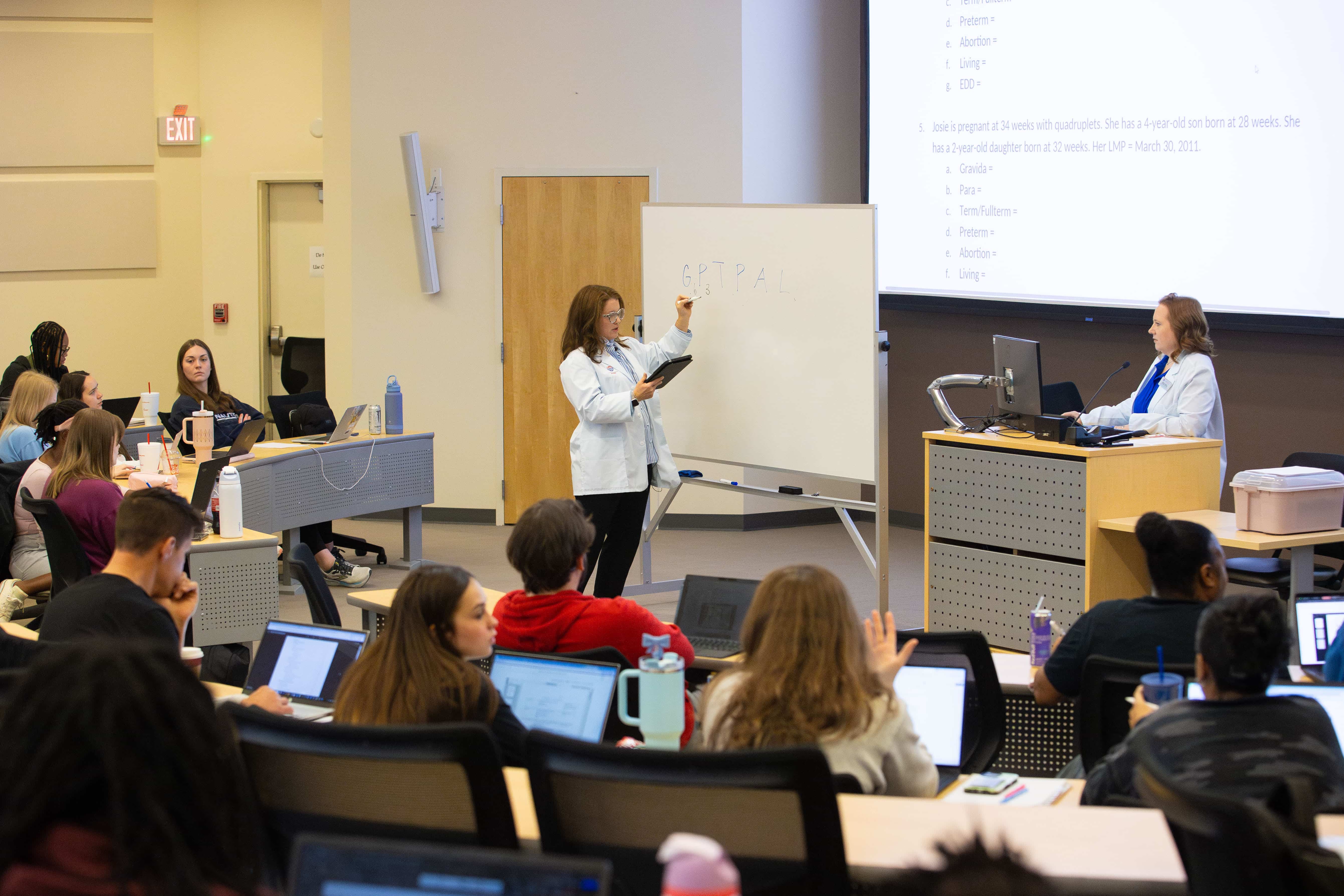 Nursing faculty writing on a whiteboard in the Newnan lecture hall.