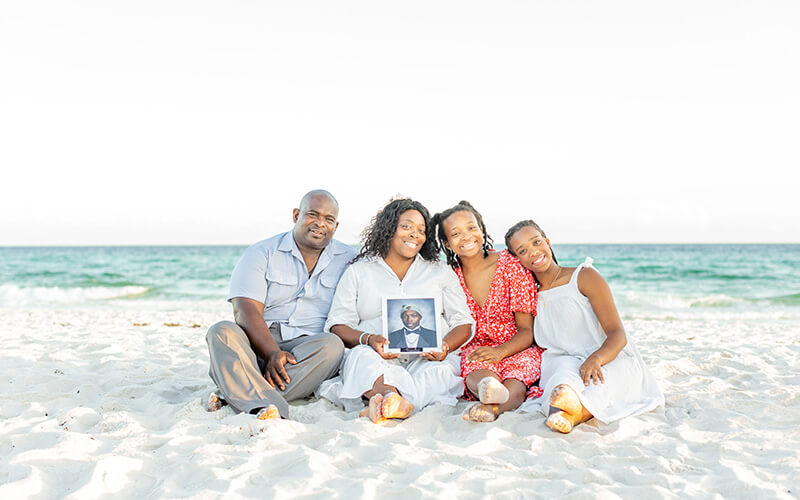 The McDaniel family holds a picture of Chase on a beach.