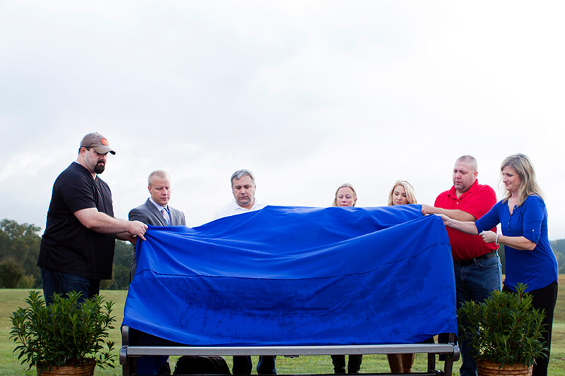Survivors unveil a memorial bench.