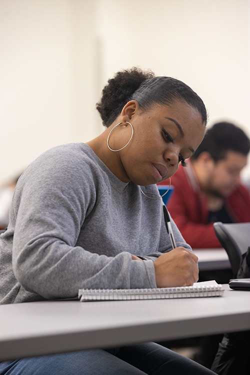 UWG student writing in a classroom