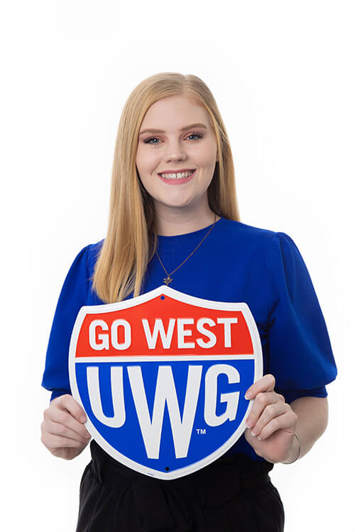 Sarah Grace Rogers holding a UWG shield sign that reads Go West