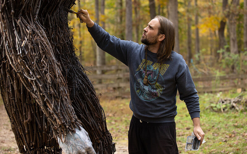 Jesse Duke paints vines on his sculpture