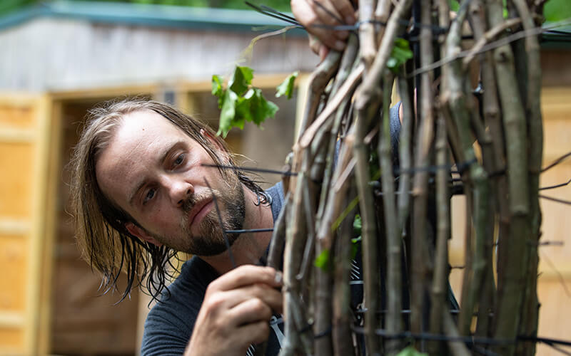 Jesse Duke begins weaving vines together for his sculpture