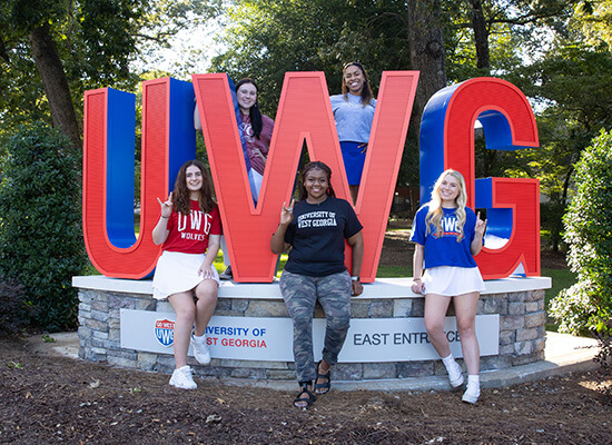 Students standing with a UWG entrance sign outside