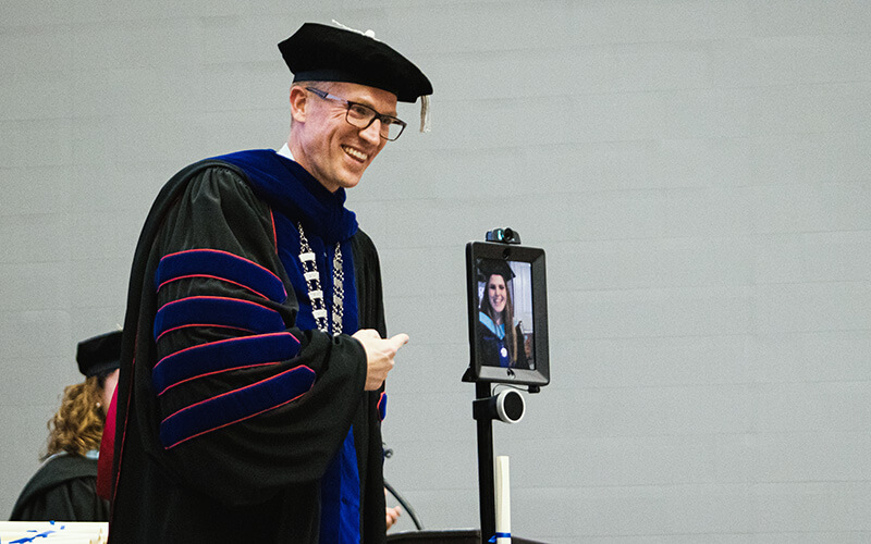 Dr. Brendan Kelly with a student graduating via robot