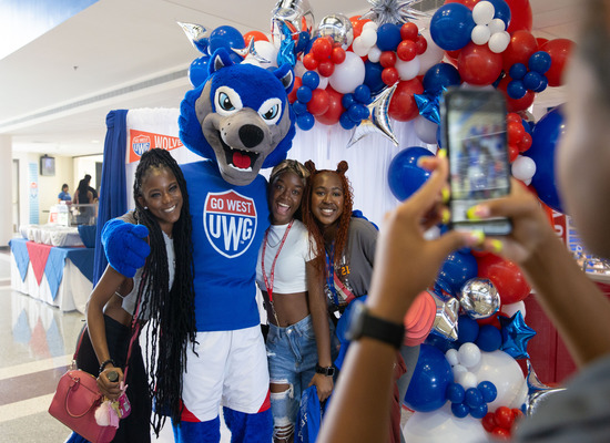 Students posing for a picture with Wolfie. 
