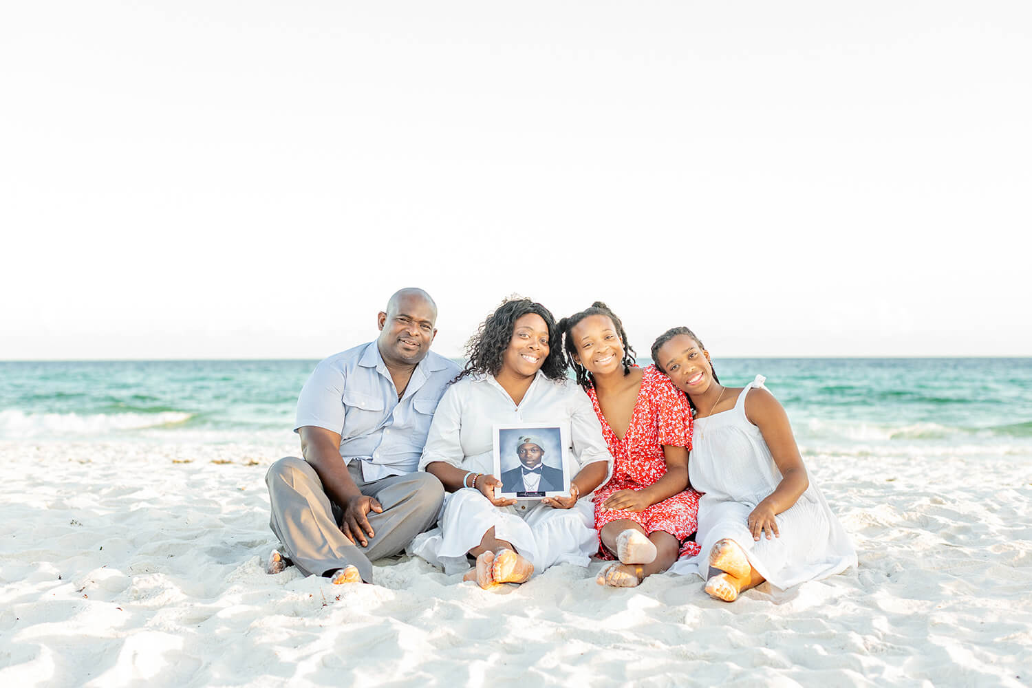 UWG alumni and family on a beach holding a photo of a loved one