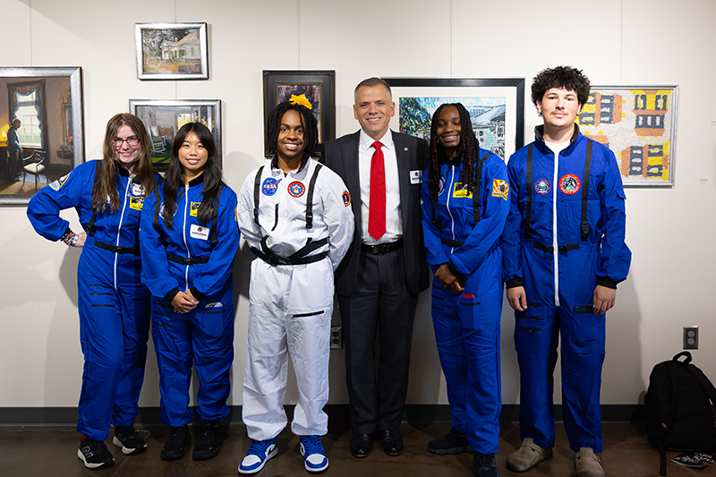 Dr. Johnson poses with students dressed in space suits