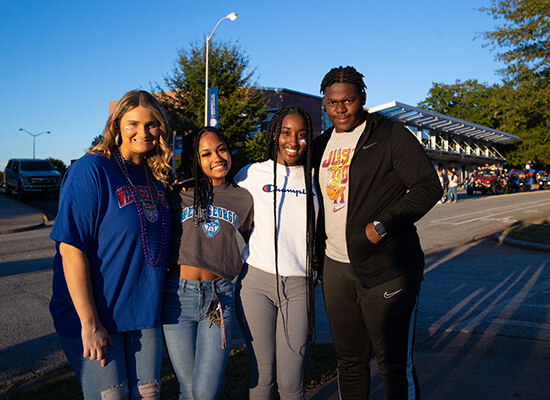 A group of smiling UWG students outdoors on campus