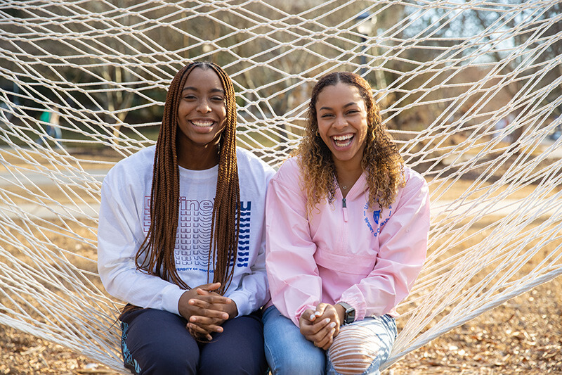 two UWG students sitting on a hammock outside on campus