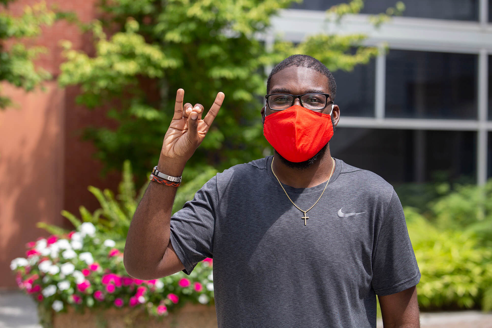Student wearing a mask giving a Wolf hand sign