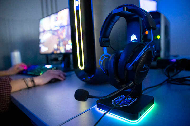 UWG Esports set of headphones sitting on a table next to a computer