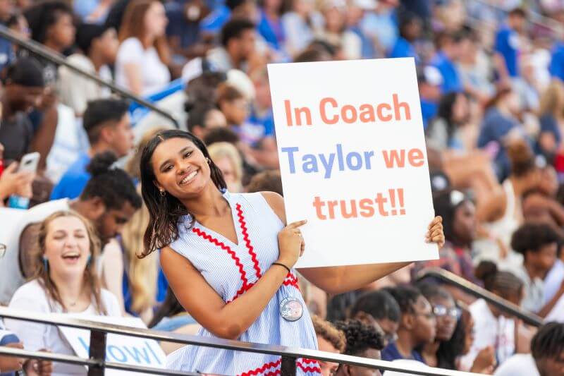 UWG Wolves fan holding up a sign that says, "In Coach Taylor we trust."