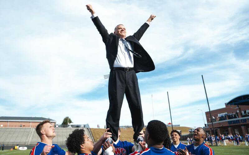 UWG President Dr. Michael Johnson is hoisted by Wolves football players