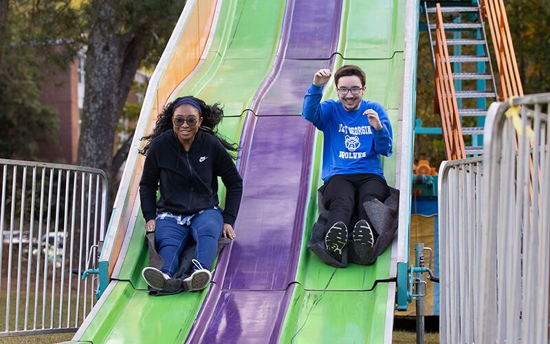 UWG students come down a slide celebrating UWG Homecoming 2023