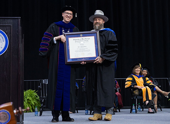 Dr. Brendan Kelly and Zac Brown hold up Brown's honorary degree from the University of West Georgia