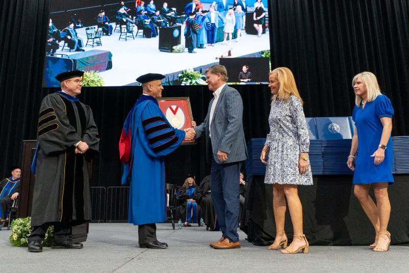 UWG President Dr. Michael Johnson hands the medallion to Bill Stone