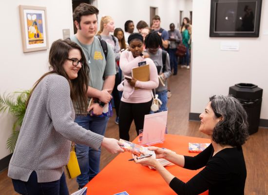 Author handing a signed book to an attendee at a UWG Culture Lab event