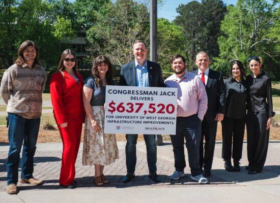 Congressman Brian Jack, center and holding a check, and UWG President Dr. Michael Johnson celebrate in Love Valley with UWG students.