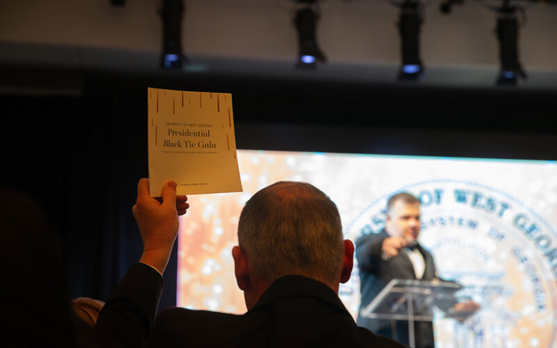 A celebrant bids on an auction item at UWG's Presidential Black Tie Gala