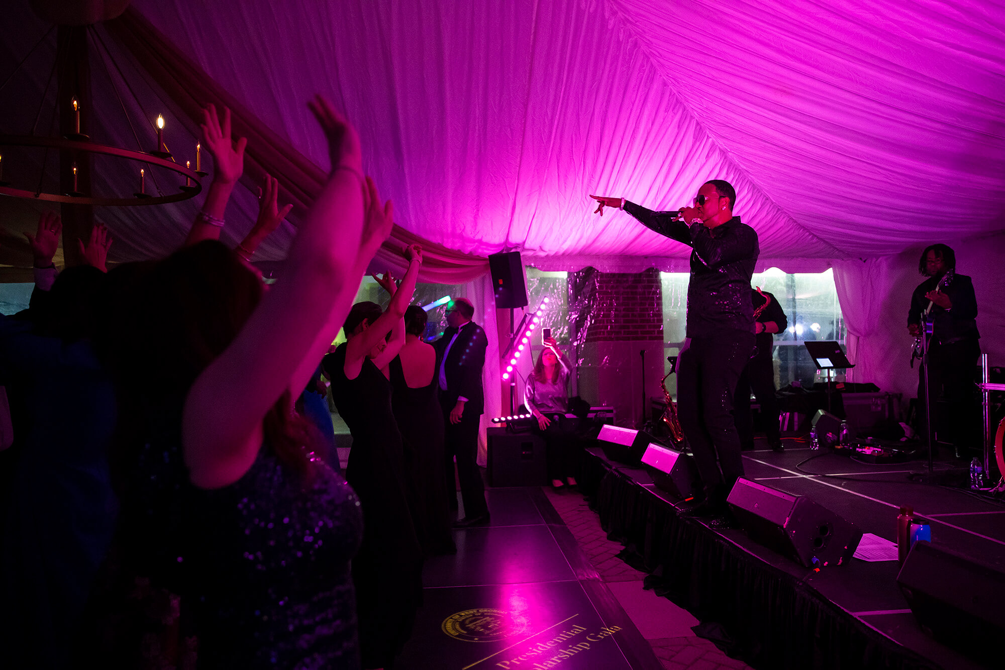 Musician onstage points to dancing audience members at the 2023 UWG Presidential Gala