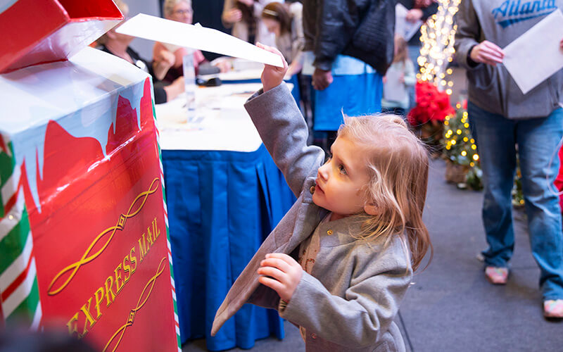 A child mailing a letter to Santa Claus.