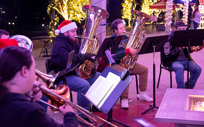 A festive holiday band with one performer wearing a Santa hat