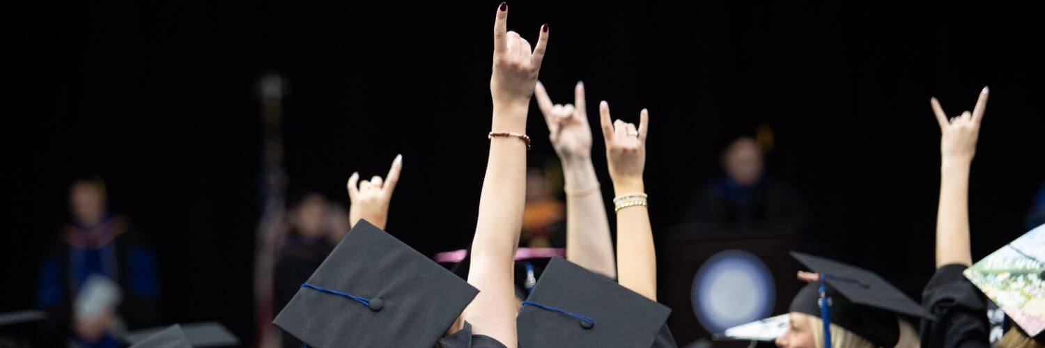UWG graduates at Spring Commencement give the "Wolves Up" hand sign