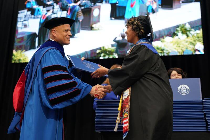 UWG president Dr. Michael Johnson hands a graduate her degree during spring commencement