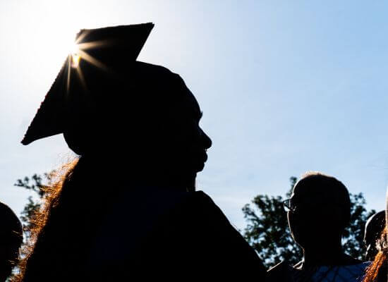 A UWG graduate silhouetted in the sun on commencement day