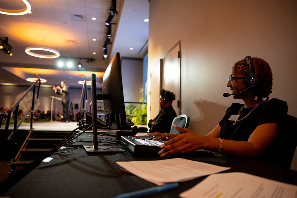 Students with UWG Productions manage the soundboard while President Brendan Kelly speaks in the background.