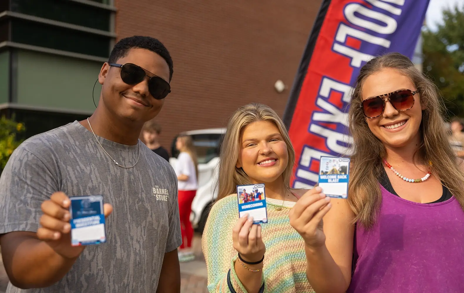 Three UWG students holding Pack Cards at Welcome Back Blast