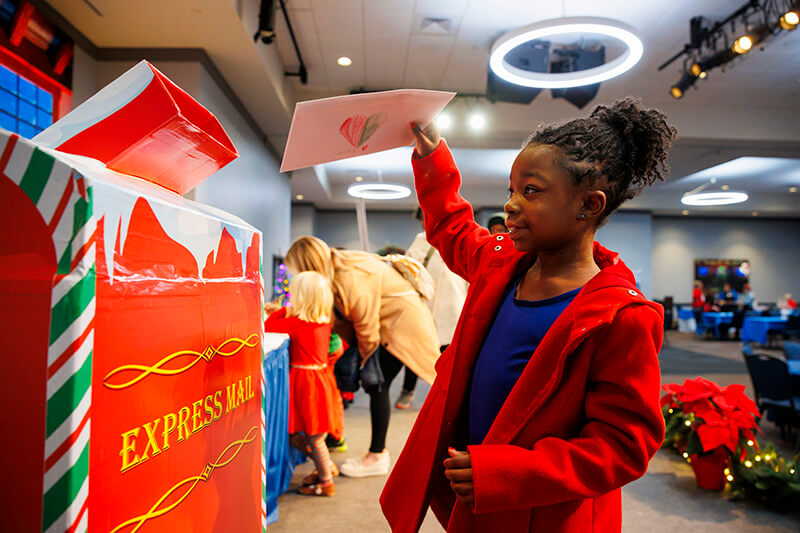 Child puts a letter to Santa in the mailbox at UWG's 2024 Winter West Wonderland