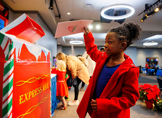 Child puts a letter to Santa in the mailbox at UWG's 2024 Winter West Wonderland