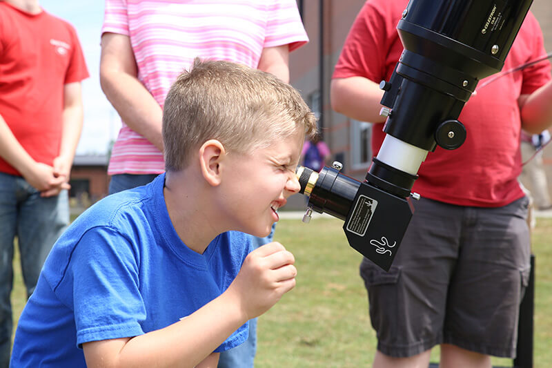 A child looks through a telescope